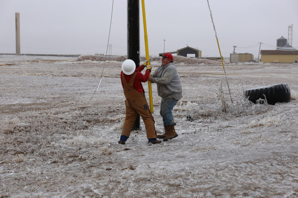 Former lineman Josh Schmidt, Victory EC’s supervisor of key accounts and business development (left), gets help from Ford County Feedyard staffer Steve Downey as he restores power to the business. (Photo By: Victory EC)