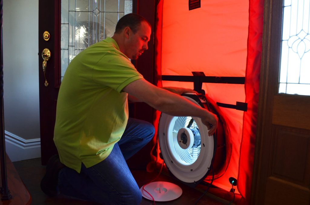 Chris Woolery is checking a house for air leaks with a blower door test under an energy efficiency program, How$martKy. (Photo By: Ivy Brashear)