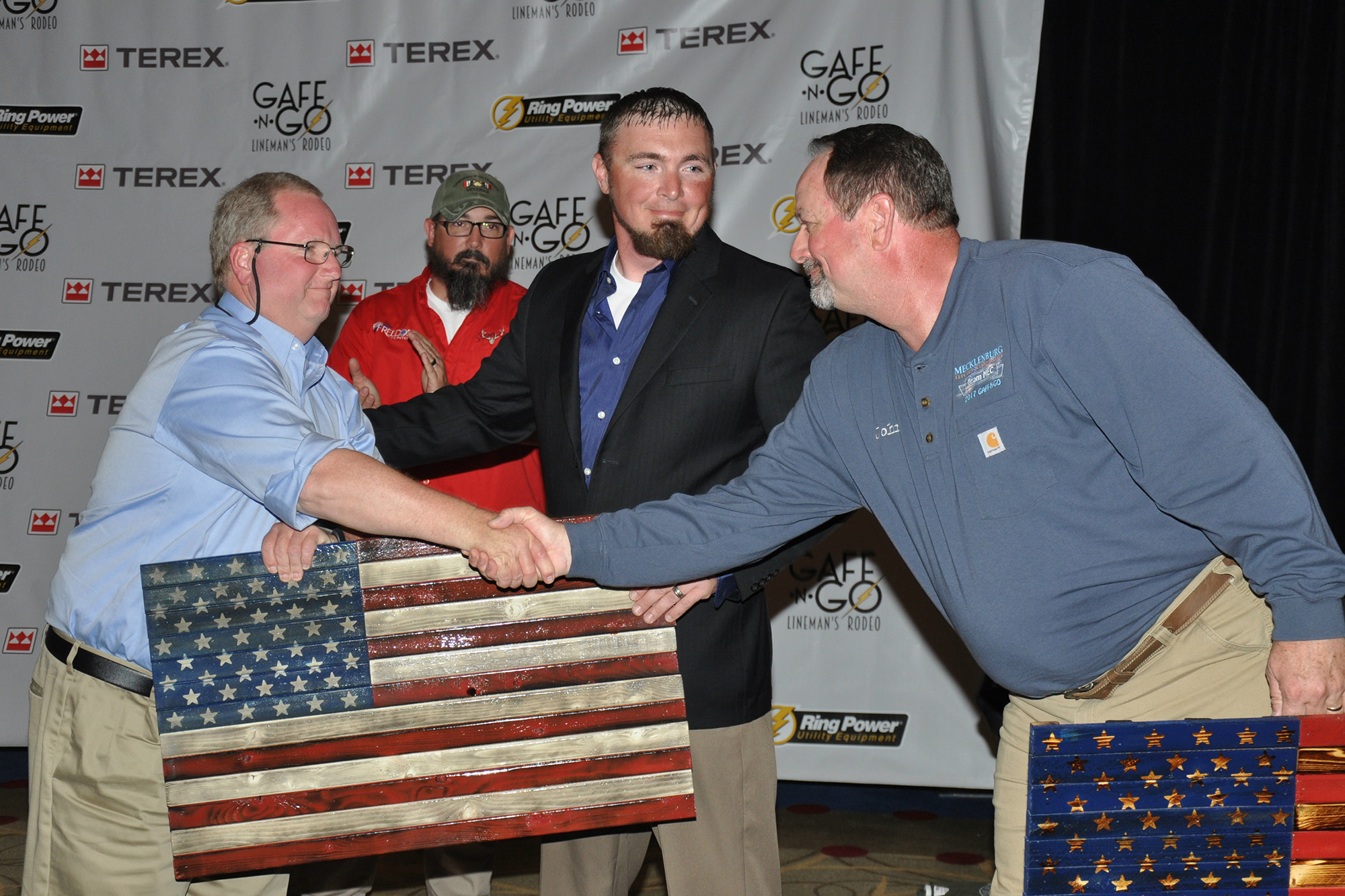Nate Humphrey (c) smiles after he presents flag gifts to CEOs Jeff Edwards (l) of Southside Electric Cooperative and John C. Lee Jr. of Mecklenburg Electric Cooperative. The two men were instrumental in establishing the power line worker school at which Humphrey trained. (Photo By: Bill Sherrod/VMDAEC)