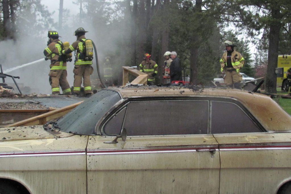 Volunteer firefighters remove a car and three motorcycles from the burning garage. (Photo By: Lisa Rosemore/Grand Rapids Herald-Review)