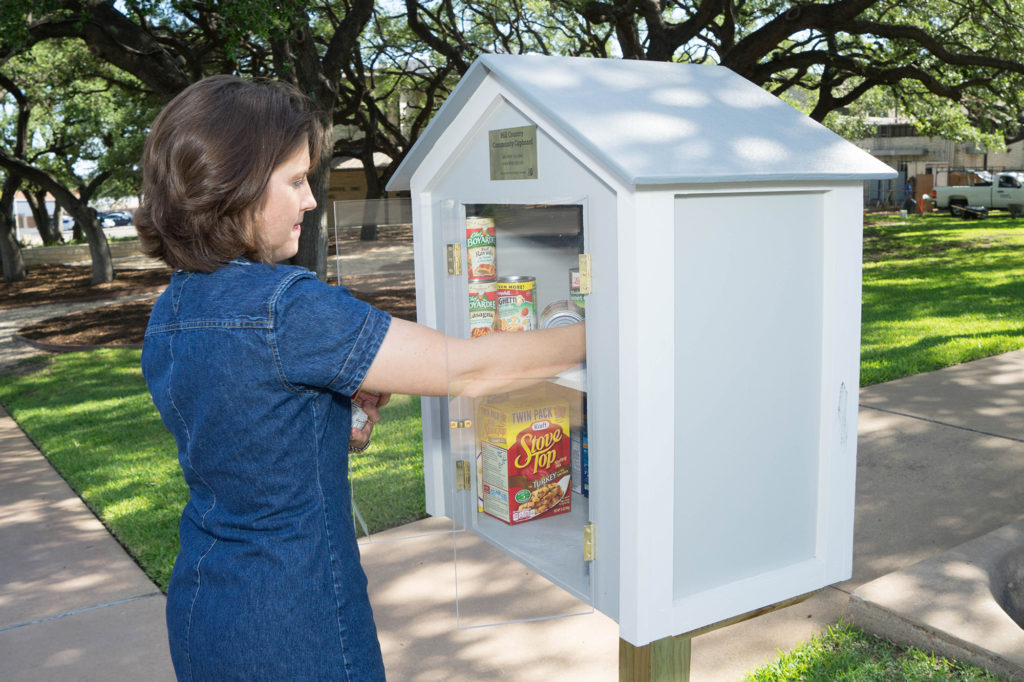 Pedernales Electric Co-op’s Audri Nelson refills the Hill Country Community Cupboard. Donations also come from local residents and community groups. (Photo By: John Larsen)