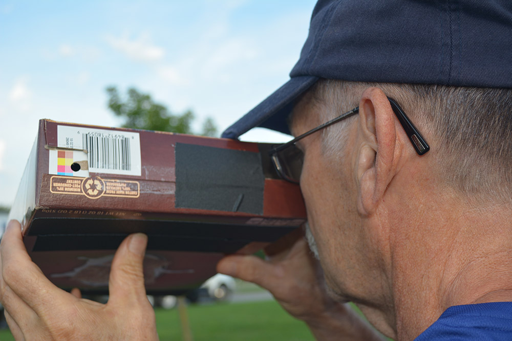 Bill Hofstetter, a member of Platte-City Electric, views the eclipse through hi homemade pinhole camera. Mr. Hofstetter’s son-in-law, Marty Kelsey, was one of the Smithsonian Institution National Air and Space Museum STEM in 30 crew who helped at the event. (Photo By: Cheryl Barnes/PCEC)
