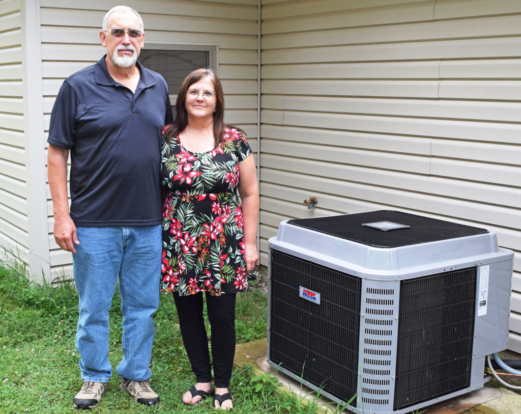 Michael and Anita Yates stand beside the heat pump purchased with financing provided by North Arkansas Electric Cooperative. (Photo by: Tori Moss)
