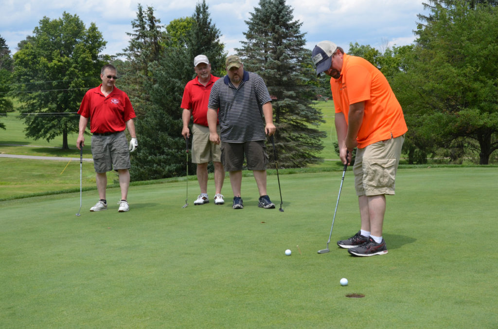 Valley REC’s Billy Ayers sinks a putt as team members look on during the 2017 Valley Rural Electric Outing, which raised $32,000. (Photo By: Valley REC)