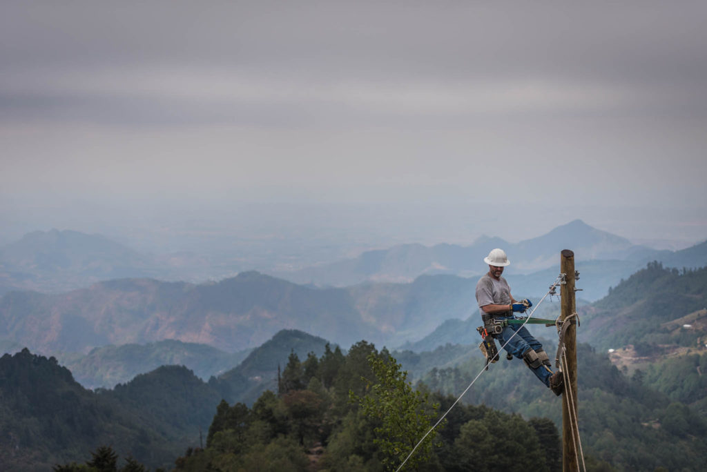 NineStar Connect lineman Jamie Bell assembles hardware atop a pole in the Guatemalan mountain village of El Zapotillo - with the country's southwestern mountains and the mountains of southern Mexico in the near and far distance. (Photo By: Ron Holcomb, Tipmont REMC)