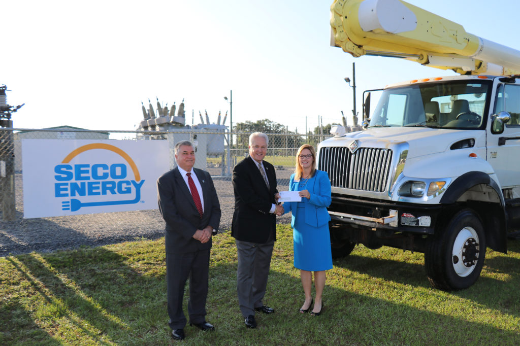 SECO Energy has been a longtime supporter of Lake-Sumter State College’s lineworker degree program. Co-op CEO Jim Duncan (center) presents the? truck title to LSSC. (Photo Courtesy of SECO Energy)