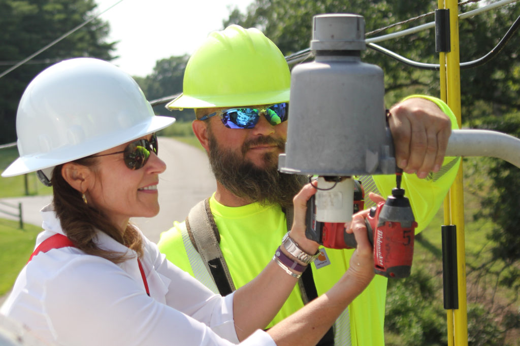 U.S. Rep. Cheri Bustos is “Cheri on Shift” as she helps Spoon River Electric Co-op’s Bill Sego install an LED bulb in a security light. (Photo By: Valerie Cheatham/AIEC)