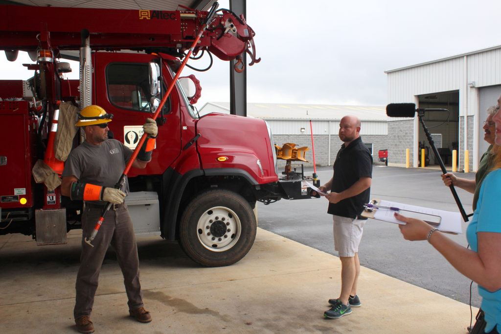 Central Virginia Electric Cooperative operations foreman Talmage Eubank demonstrates hot stick work for a production crew from The Weather Channel. (Photo By: Laura Emery/Cooperative Living)