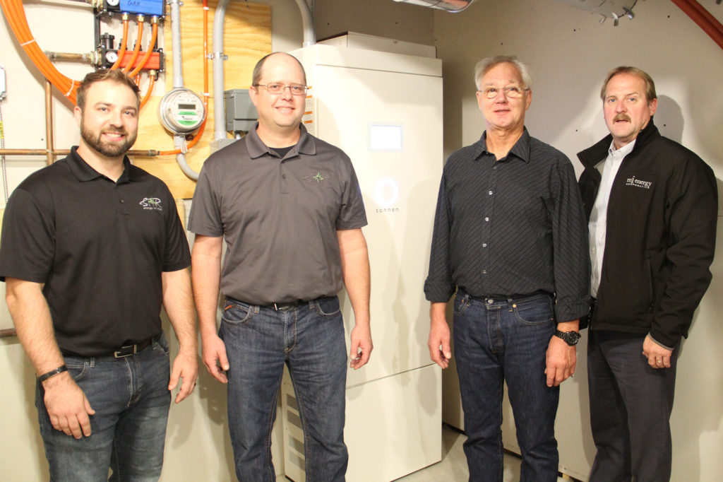 L-R: Kent Whitcomb, STAR Energy Services, engineering technician; Tony Kassa, STAR Energy Services, master electrician; Ian Webster, MiEnergy Cooperative member, and Brian Krambeer, MiEnergy Cooperative president/CEO, at the commissioning of the first residential battery in the pilot. MiEnergy is a co-owner of STAR Energy Services. (Photo Credit: MiEnergy)