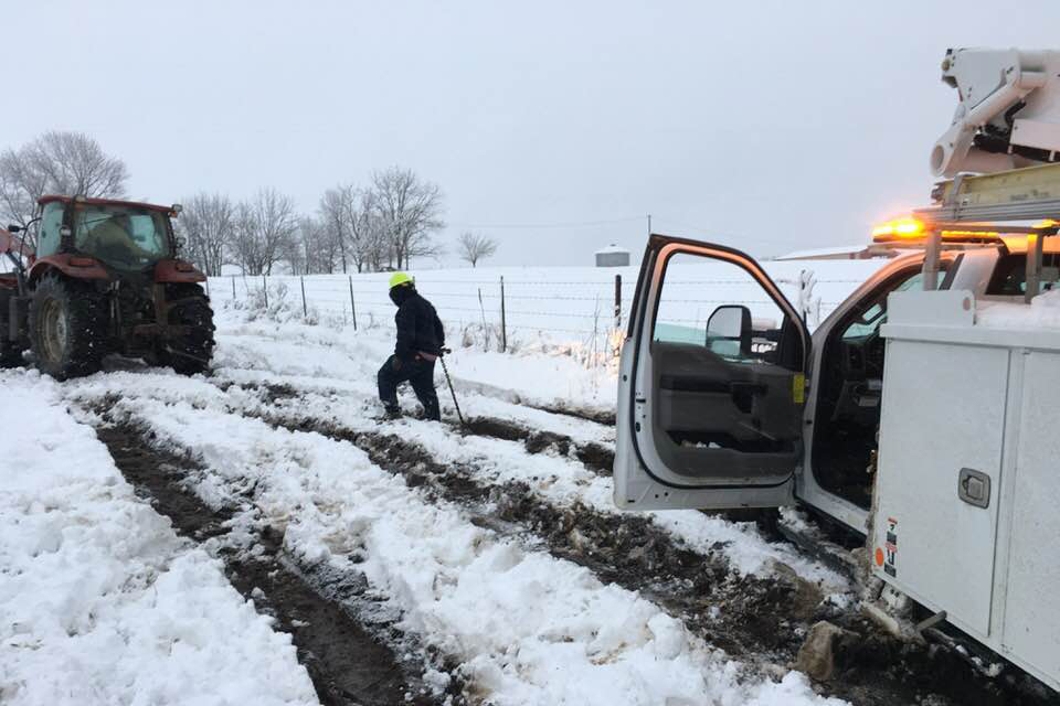 An Osage Valley Electric Cooperative line technician prepares to have his line truck towed by a member as he works to restore service in Missouri. (Photo By: Osage Valley EC)