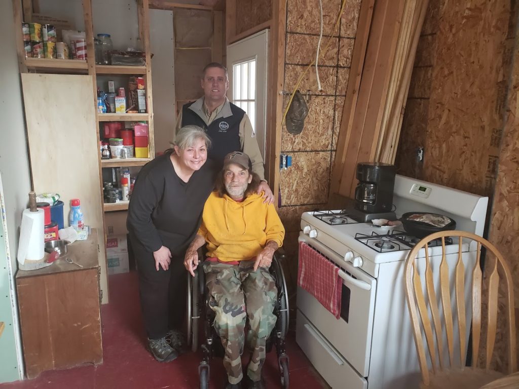 Tina and Geoff Wilson (in wheelchair), new members of Moon Lake Electric Association, with the co-op’s Curtis Miles before the couple’s Talmage, Utah, home received power. (Photo By: Yankton Johnson)