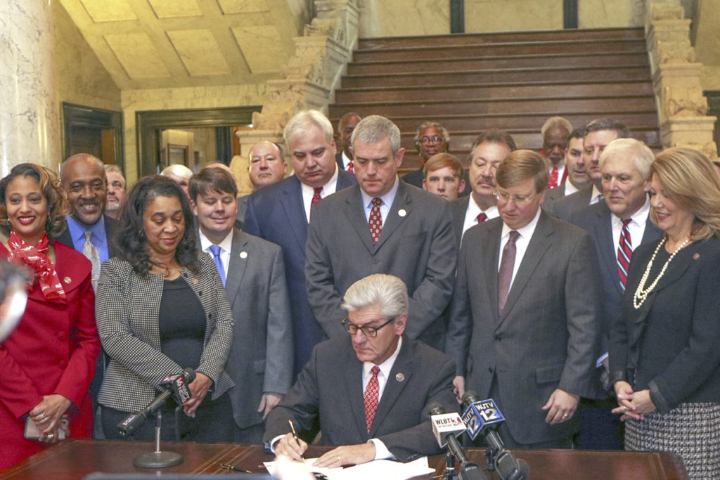 Mississippi Gov. Phil Bryant signs a law to allow electric co-ops to pursue broadband as supporters, including statewide CEO Michael Callahan (third from left, second row), look on. (Photo By: Electric Cooperatives of Mississippi)