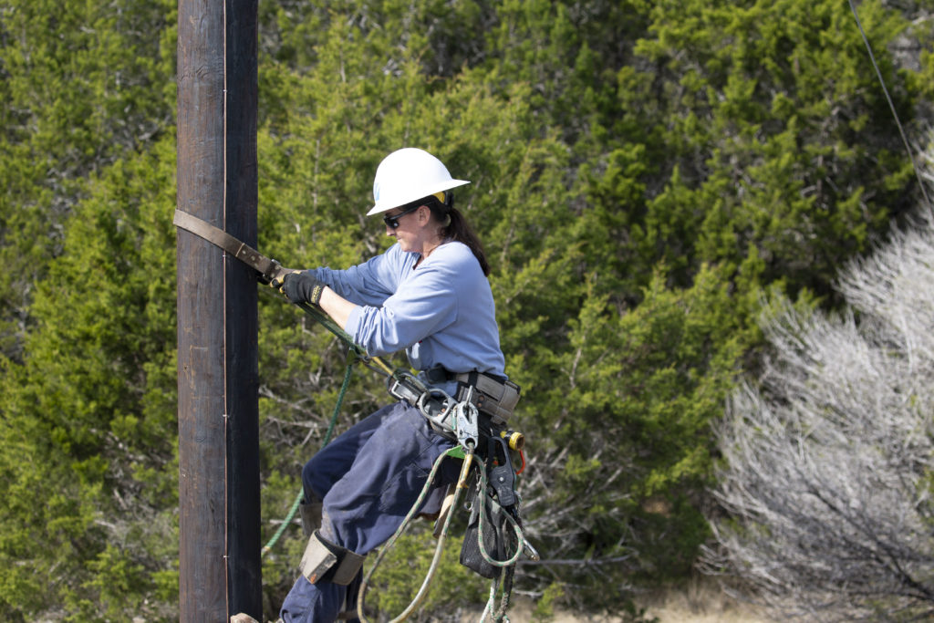 Pedernales Electric Cooperative apprentice lineworker Kaitlyn Vaillancourt climbs a recently installed distribution pole to prepare it for service to new members. (Photo By: Alexis Matsui/NRECA)