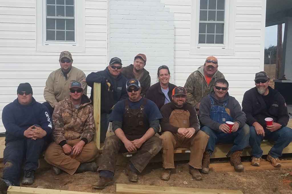 Employees of Mecklenburg Electric Cooperative take a break during construction of the wheelchair ramp they would finish later that day at their co-workers’ home. (Photo By: Priscilla Lawson Whirley)