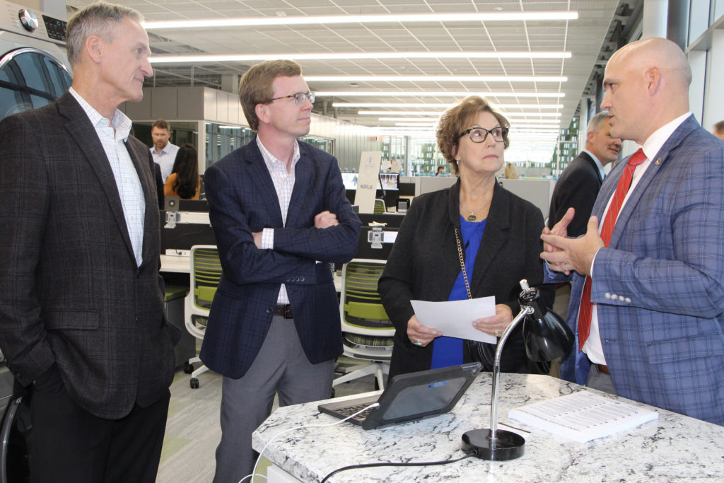 East River Electric Power Cooperative’s Chris Studer, far right, talks to visitors at the grand opening of the Connected Home Research Project at Dakota State University’s Cyber Labs in Madison, South Dakota. The visitors, from left, are: former South Dakota Gov. Dennis Daugaard, U.S. Rep. Dusty Johnson and former South Dakota first lady Linda Daugaard. (Photo Courtesy: East River Electric Cooperative)