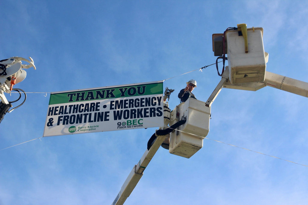 Barry Electric Cooperative in southwest Missouri hoisted a large banner at a busy intersection thanking all the frontline workers. Lineworker Brian Robbins gives a thumbs-up.( Photo By: Barry Electric Cooperative)