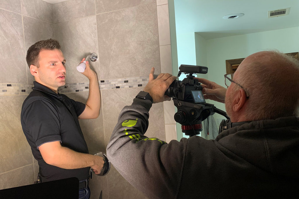 AECC's Mitch Ross demonstrates how to change a showerhead as the state's videographer, Gary Bean, records the process for use in the CHESS Moves video series. (Photo By: AECC)