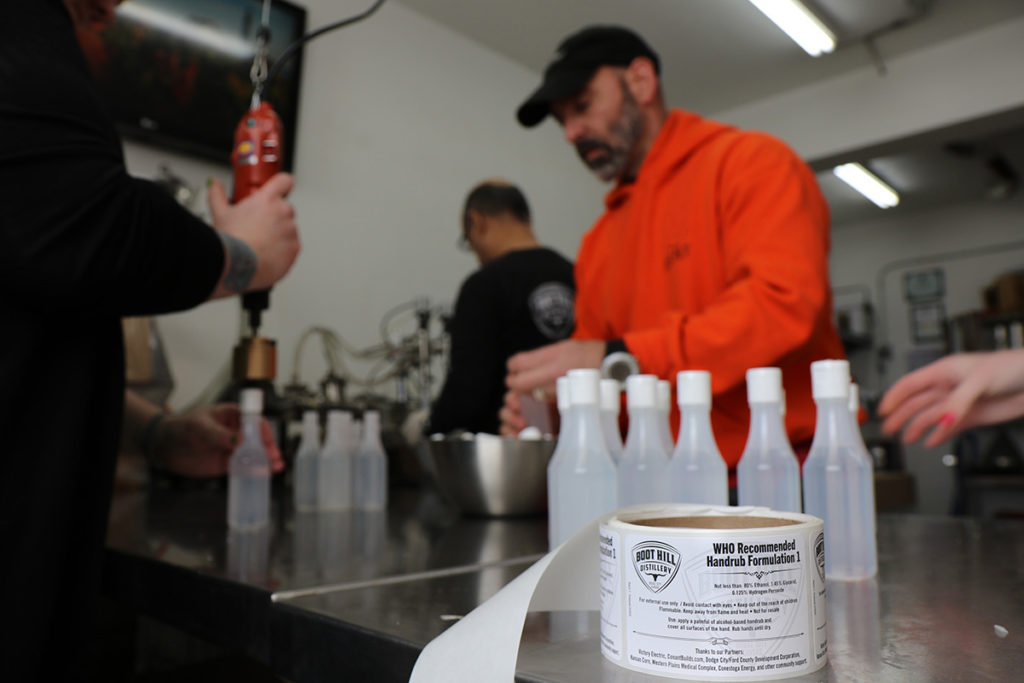 Victory Electric Cooperative CEO Shane Laws (center) helps bottle hand cleanser at a distillery in Dodge City, Kansas. (Photo By: Jerri Whitley/Victory EC)