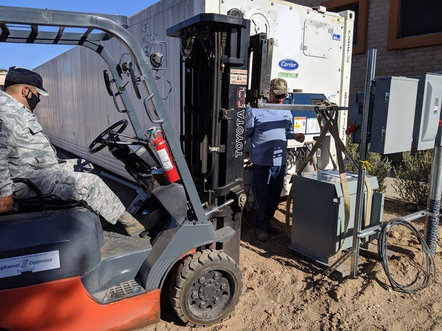 2.	Trico Electric Cooperative’s Jaime Esparza and Master Sgt. Omar Fernandez (l) install a transformer at the Sahuarita Food Bank. (Photo Courtesy: Trico EC)
